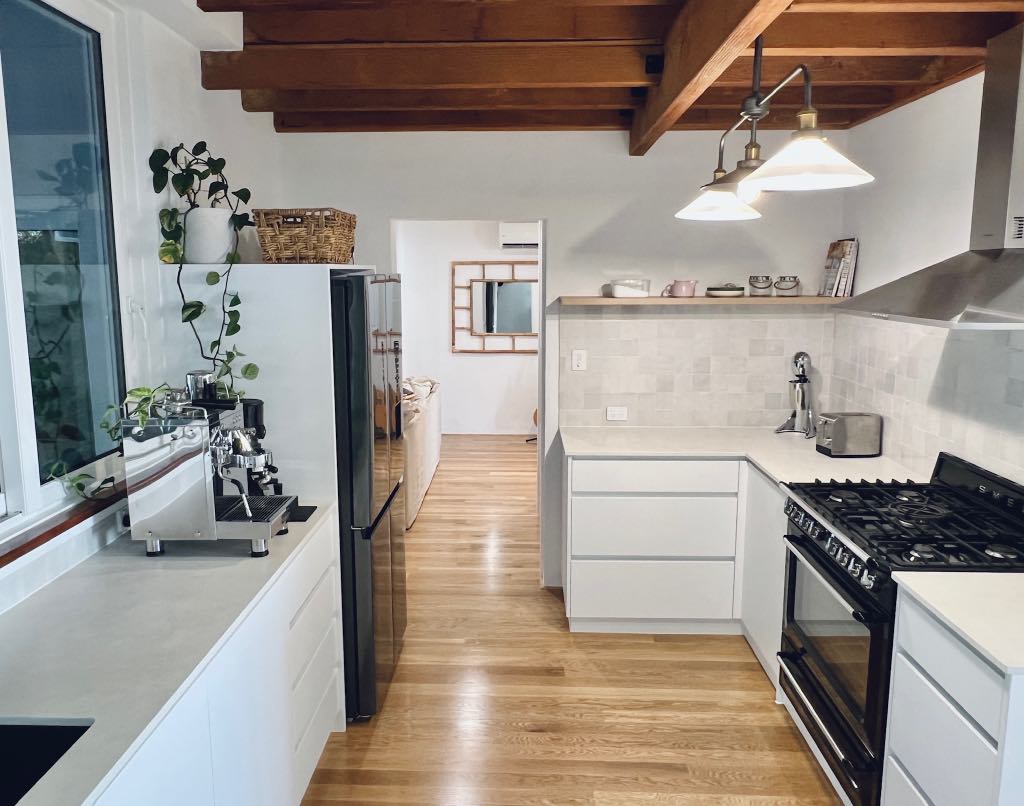 Kitchen with white cabinetry, a black gas range and timber beams overhead