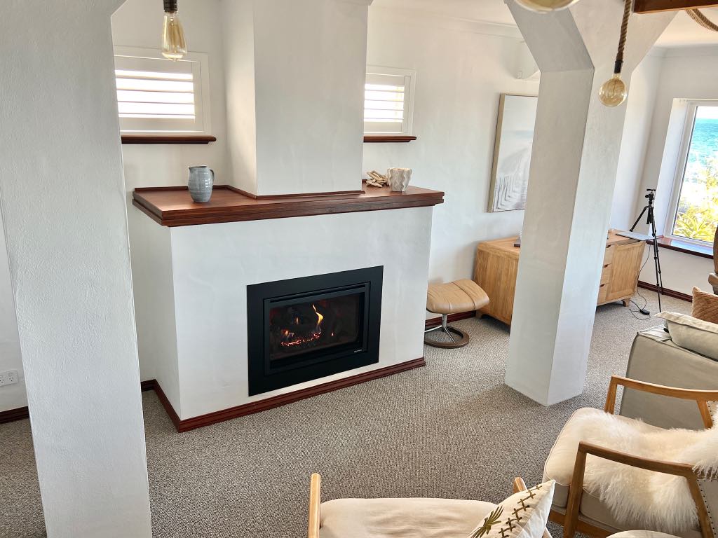 Fireplace with a timber mantel between white columns in the living room