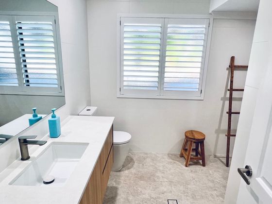 Bathroom with a long timber vanity, plantation shutters and a towel ladder