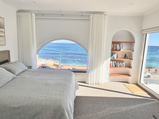 Main bedroom with an arched window framing the ocean and an arched bookshelf niche