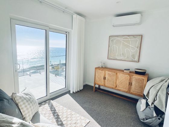 Bedroom with sliding doors to the balcony and the ocean beyond, and a cane sideboard