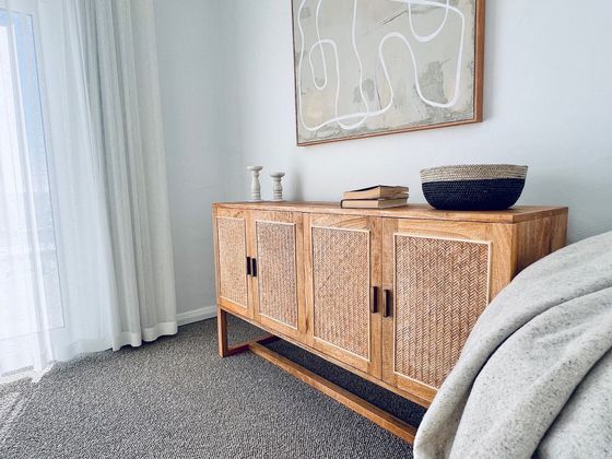 Cane sideboard beneath an abstract artwork