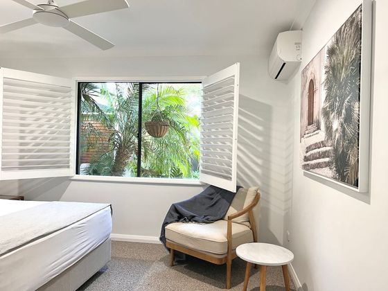 Armchair and side table beside a window with a palm outside