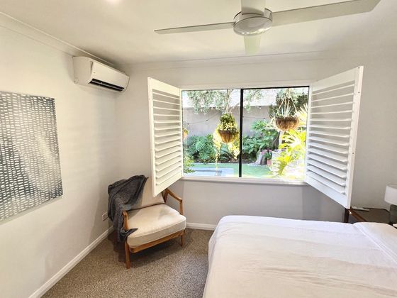 Armchair beside open shutters with the garden beyond