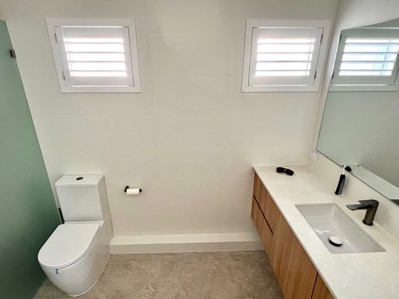 Ensuite with a timber vanity, a wide mirror and high shuttered windows