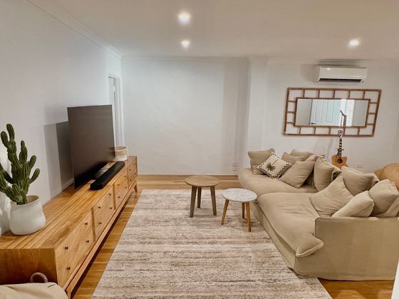 Family room with a television on a long timber sideboard, a corner sofa and a woven rug
