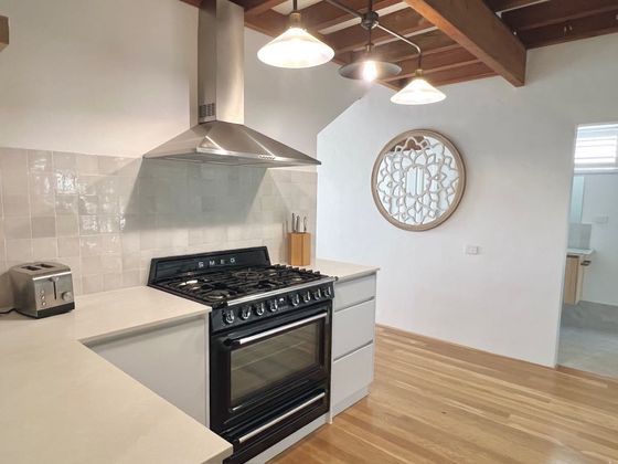 Black Smeg gas range under a steel canopy with pendant lights above