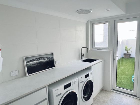 Laundry with washer and dryer under a long bench and a door to the side lawn