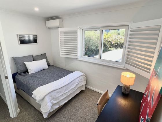 Room with a double bed, shuttered window and a desk with a lamp
