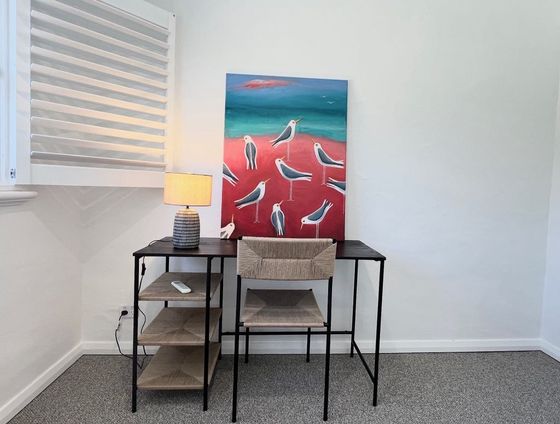 Desk with a lamp beneath a painting of seagulls